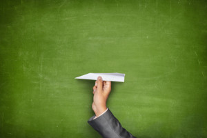 Black blank blackboard with hand holding paper plane