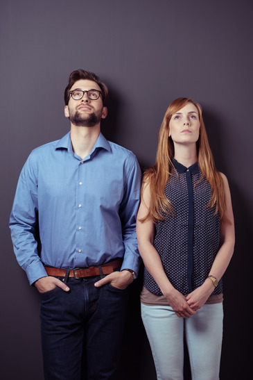 Young Professional Couple Looking Up Against Gray